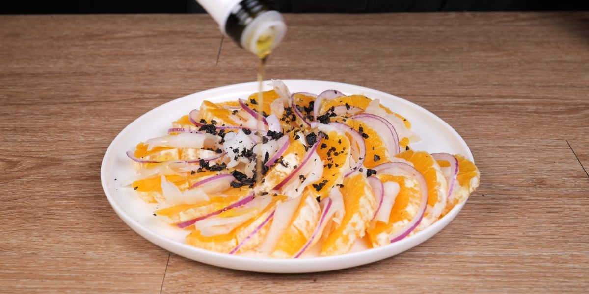 Verter aceite de oliva virgen extra en Ensalada de bacalao con naranja